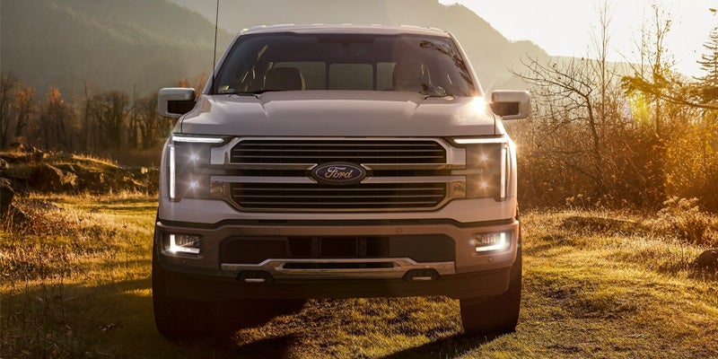 Ford F-150 parked on a grassy field as the sun is setting behind the vehicle